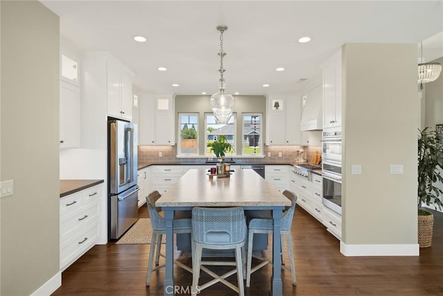 5031 San Juanico Dr, Chico, CA 95973 - kitchen with appliances with stainless steel finishes, white cabinetry, dark wood-style flooring, a kitchen breakfast bar, and recessed lighting