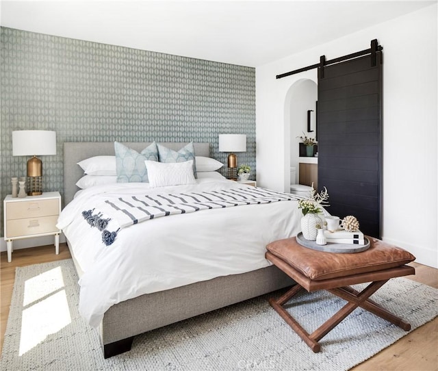19476 Woodlands Dr, Huntington Beach, CA 92648 - bedroom featuring wallpapered walls, a barn door, wood finished floors, and arched walkways