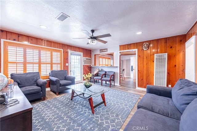 4759 Cochran St, Simi Valley, CA 93063 - living area featuring a heating unit, wooden walls, a ceiling fan, wood finished floors, and a textured ceiling