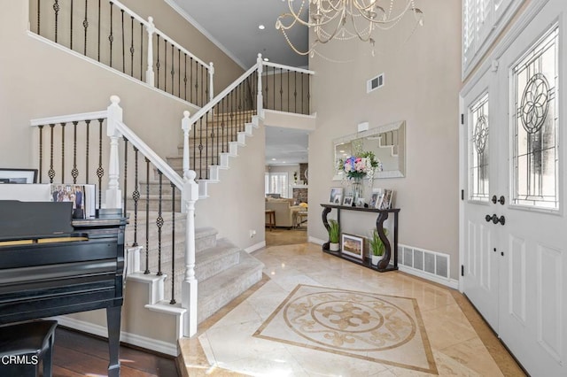 2561 Upper Bay Dr, Oxnard, CA 93036 - entryway featuring inlaid floor details, a high ceiling, stairway, a chandelier, and marble tiled floors