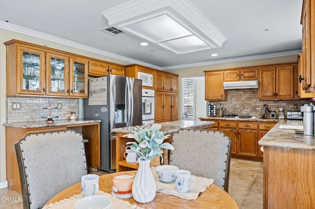 2561 Upper Bay Dr, Oxnard, CA 93036 - kitchen with white appliances, crown molding, tasteful backsplash, brown cabinetry, and light stone countertops