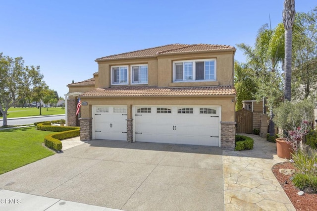 2561 Upper Bay Dr, Oxnard, CA 93036 - mediterranean / spanish-style home with a tiled roof, concrete driveway, stucco siding, an attached garage, and stone siding