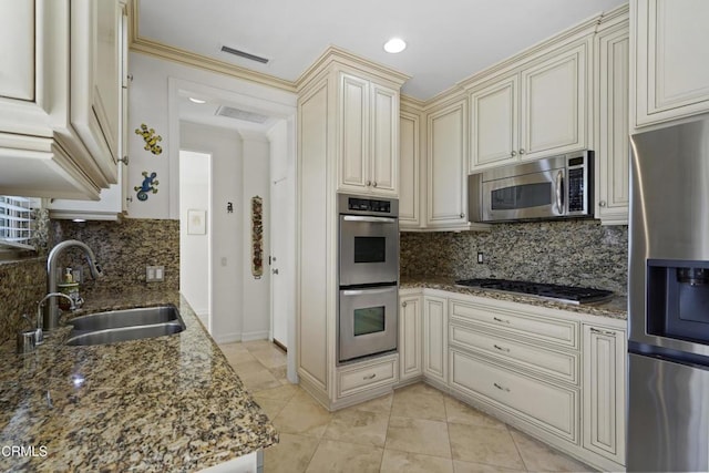 630 S Orange Grove Blvd Unit 5, Pasadena, CA 91105 - kitchen with appliances with stainless steel finishes, cream cabinetry, dark stone counters, decorative backsplash, and light tile patterned flooring