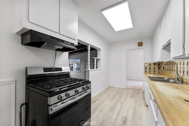 11749 Clarkman St, Santa Fe Springs, CA 90670 - kitchen with stainless steel gas range, under cabinet range hood, white cabinets, tasteful backsplash, and light wood-style floors