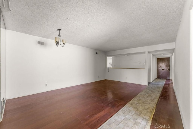 10527 S Wilton Pl, Los Angeles, CA 90047 - unfurnished living room featuring wood finished floors, a textured ceiling, and a chandelier