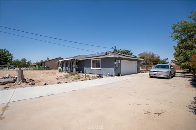 7681 Newhall Ave, Hesperia, CA 92345 - view of front of house with roof mounted solar panels, a garage, driveway, and stucco siding