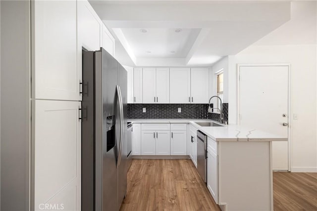 5910 Rancho Mission Rd Unit 27, San Diego, CA 92108 - kitchen featuring stainless steel appliances, a tray ceiling, light wood finished floors, a peninsula, and decorative backsplash