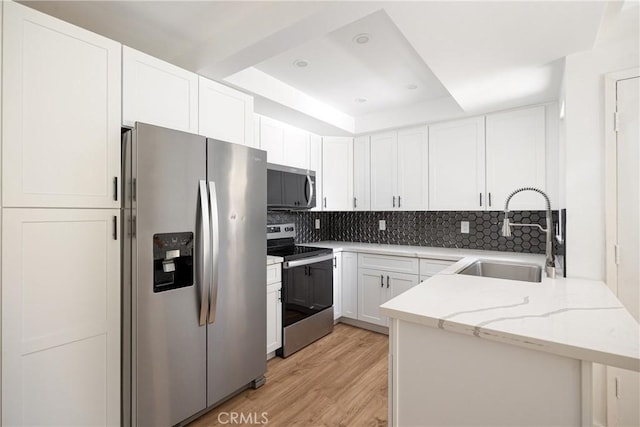 5910 Rancho Mission Rd Unit 27, San Diego, CA 92108 - kitchen featuring stainless steel appliances, a raised ceiling, tasteful backsplash, light stone countertops, and light wood-style flooring