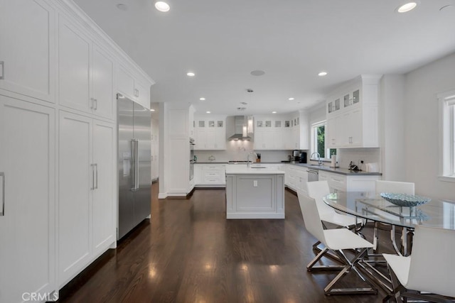 15460 La Maida St, Sherman Oaks, CA 91403 - kitchen with built in fridge, a kitchen island with sink, white cabinets, wall chimney range hood, and glass insert cabinets
