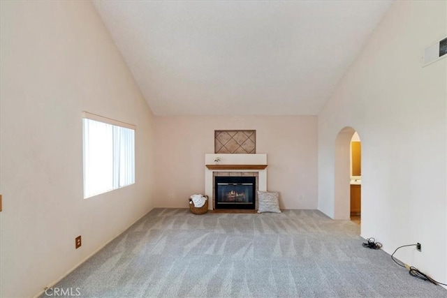 10151 Saddlehill Ter, Rancho Cucamonga, CA 91737 - unfurnished living room featuring carpet flooring, arched walkways, a tiled fireplace, and high vaulted ceiling