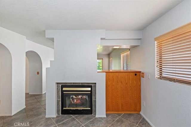 10151 Saddlehill Ter, Rancho Cucamonga, CA 91737 - unfurnished living room featuring a tile fireplace, arched walkways, and tile patterned flooring