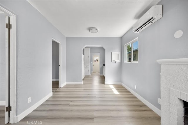 1163 W 3rd St, Pomona, CA 91766 - hallway with an AC wall unit, arched walkways, and light wood finished floors