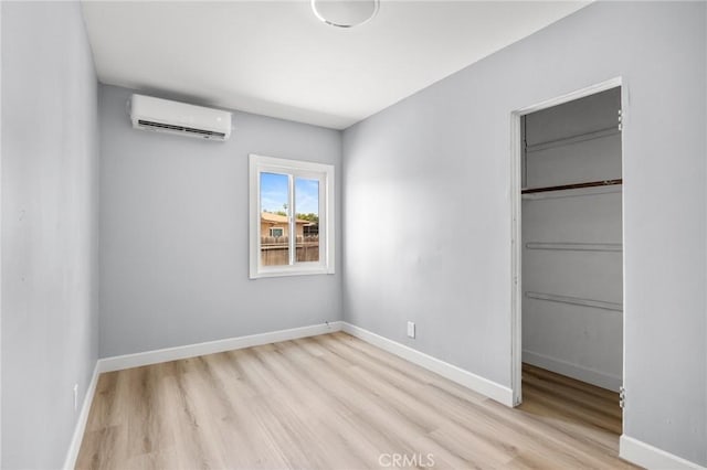 1163 W 3rd St, Pomona, CA 91766 - unfurnished bedroom featuring an AC wall unit, wood finished floors, a closet, and a walk in closet