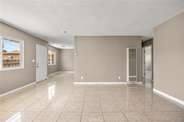 1163 W 3rd St, Pomona, CA 91766 - empty room featuring a heating unit, a textured ceiling, and light tile patterned floors