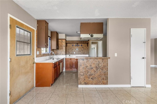 1163 W 3rd St, Pomona, CA 91766 - kitchen featuring light countertops, tasteful backsplash, light tile patterned flooring, a textured ceiling, and brown cabinetry