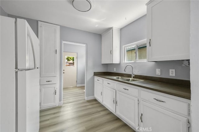 1163 W 3rd St, Pomona, CA 91766 - kitchen with freestanding refrigerator, dark countertops, white cabinetry, and light wood-style flooring