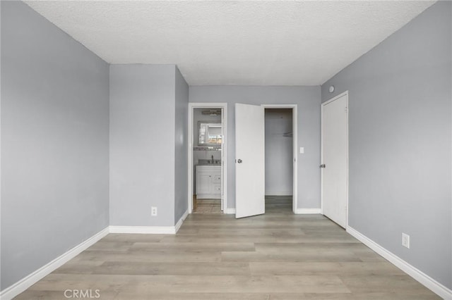 1163 W 3rd St, Pomona, CA 91766 - unfurnished bedroom featuring wood finished floors, a textured ceiling, connected bathroom, and a closet