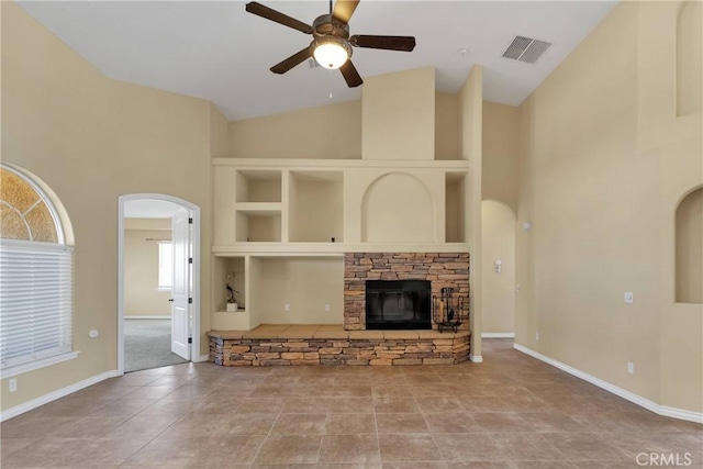 21777 Poppy Rd, Apple Valley, CA 92308 - unfurnished living room featuring arched walkways, ceiling fan, high vaulted ceiling, a stone fireplace, and tile patterned flooring