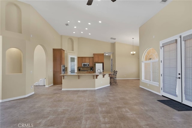 21777 Poppy Rd, Apple Valley, CA 92308 - kitchen with stainless steel appliances, high vaulted ceiling, a ceiling fan, brown cabinets, and a kitchen bar