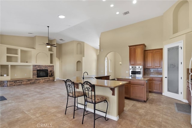 21777 Poppy Rd, Apple Valley, CA 92308 - kitchen featuring a kitchen island with sink, stainless steel oven, a breakfast bar area, ceiling fan, and high vaulted ceiling