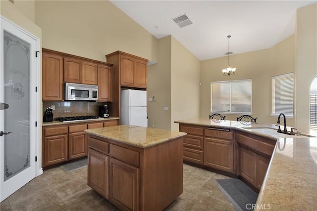 21777 Poppy Rd, Apple Valley, CA 92308 - kitchen featuring stainless steel microwave, freestanding refrigerator, high vaulted ceiling, backsplash, and a center island