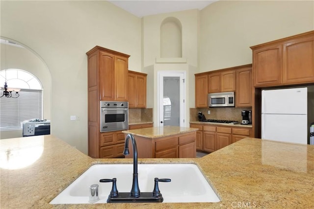 21777 Poppy Rd, Apple Valley, CA 92308 - kitchen featuring appliances with stainless steel finishes, backsplash, light stone counters, a chandelier, and a high ceiling