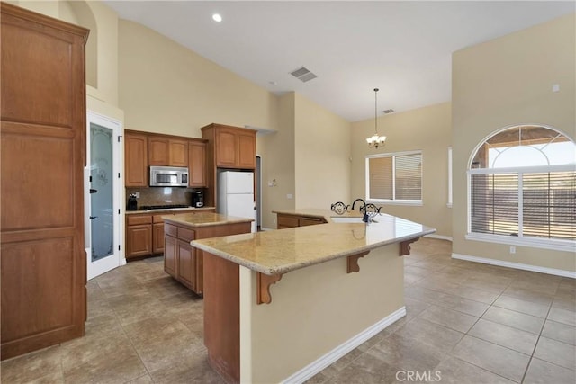 21777 Poppy Rd, Apple Valley, CA 92308 - kitchen featuring stainless steel microwave, a large island, a chandelier, freestanding refrigerator, and backsplash