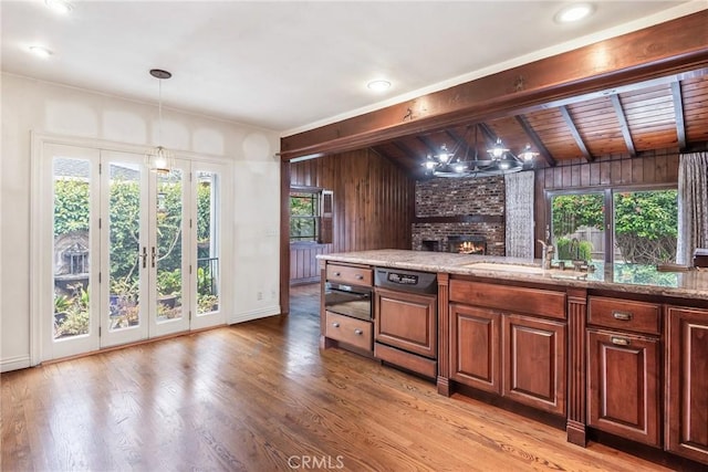2322 W 156th St, Gardena, CA 90249 - kitchen with a brick fireplace, dishwasher, hanging light fixtures, light wood-style flooring, and wooden walls