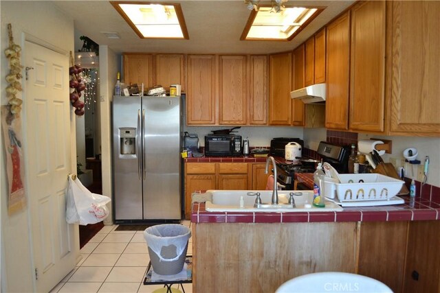 31811 Whispering Palms Trl, Cathedral City, CA 92234 - kitchen with stainless steel appliances, under cabinet range hood, tile countertops, light tile patterned flooring, and a peninsula