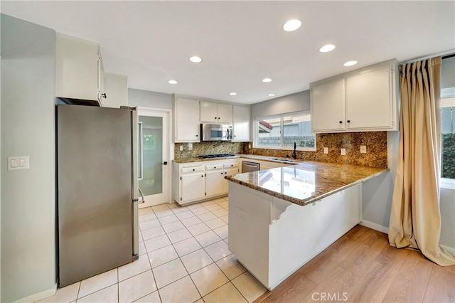 3811 Algonaut Dr, Calabasas, CA 91302 - kitchen with appliances with stainless steel finishes, a peninsula, decorative backsplash, white cabinetry, and recessed lighting