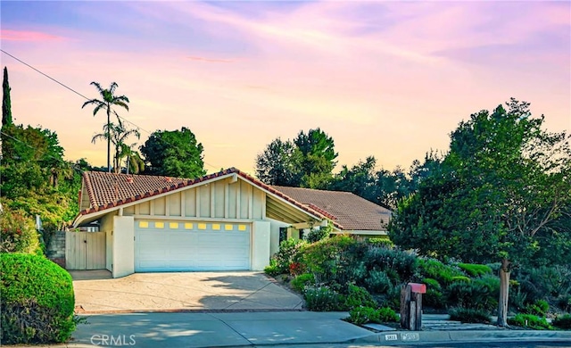 3811 Algonaut Dr, Calabasas, CA 91302 - view of front of house with a tiled roof, board and batten siding, a garage, concrete driveway, and stucco siding