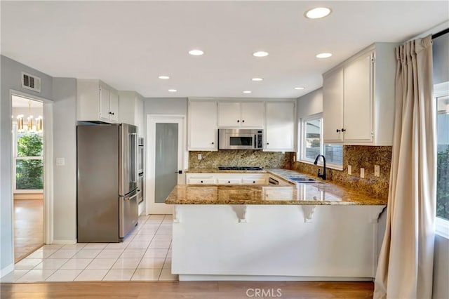 3811 Algonaut Dr, Calabasas, CA 91302 - kitchen featuring stainless steel appliances, a peninsula, healthy amount of natural light, stone counters, and recessed lighting