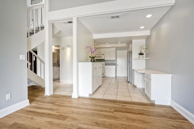 2315 Nicklaus Dr, Oceanside, CA 92056 - kitchen with white microwave, freestanding refrigerator, white cabinets, light wood-style floors, and open shelves