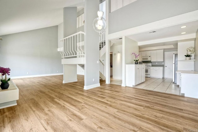 2315 Nicklaus Dr, Oceanside, CA 92056 - unfurnished living room featuring stairway, light wood finished floors, and a towering ceiling