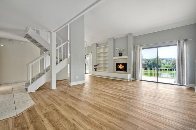 2315 Nicklaus Dr, Oceanside, CA 92056 - unfurnished living room with light wood-style flooring, stairs, a fireplace, and built in features