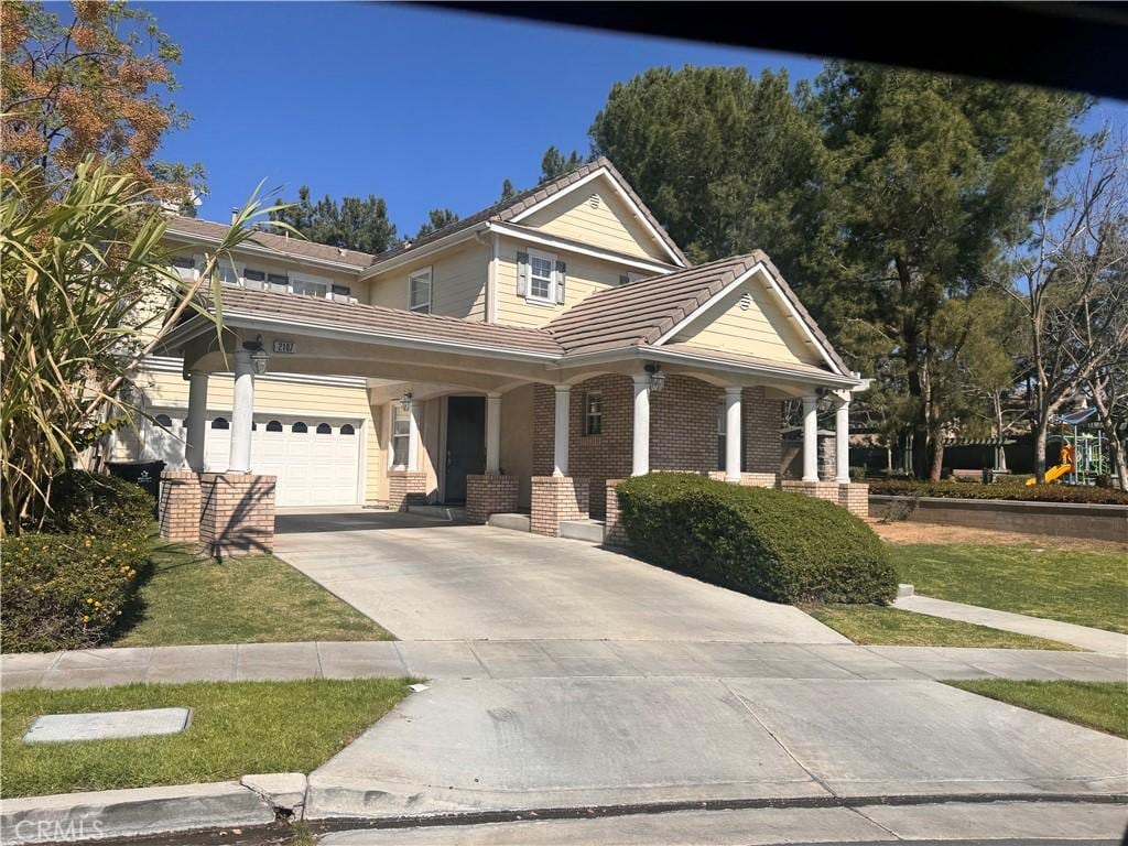 2107 Root St, Fullerton, CA 92833 - view of front of house featuring a tile roof, covered porch, driveway, a garage, and brick siding