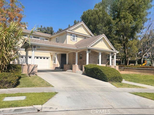 2107 Root St, Fullerton, CA 92833 - view of front facade with driveway, a tiled roof, covered porch, brick siding, and a front lawn