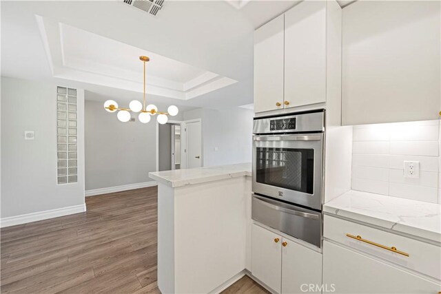 390 S Sepulveda Blvd Unit 105, Los Angeles, CA 90049 - kitchen with oven, a warming drawer, a peninsula, white cabinetry, and light wood-style flooring