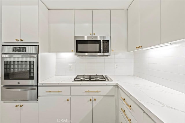 390 S Sepulveda Blvd Unit 105, Los Angeles, CA 90049 - kitchen featuring a warming drawer, stainless steel appliances, white cabinetry, backsplash, and light stone countertops