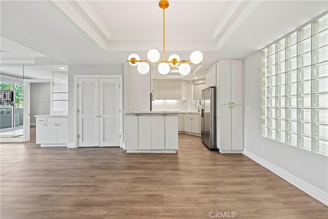 390 S Sepulveda Blvd Unit 105, Los Angeles, CA 90049 - kitchen with a tray ceiling, stainless steel fridge, white cabinetry, light countertops, and wood finished floors