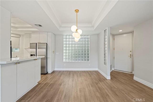 390 S Sepulveda Blvd Unit 105, Los Angeles, CA 90049 - unfurnished dining area with a raised ceiling and light wood-type flooring