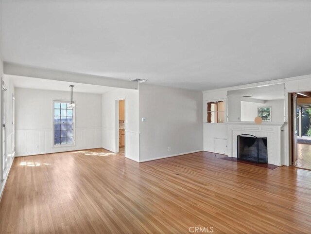13510 Valleyheart Dr N, Sherman Oaks, CA 91423 - unfurnished living room featuring light wood-type flooring, a wainscoted wall, and a brick fireplace