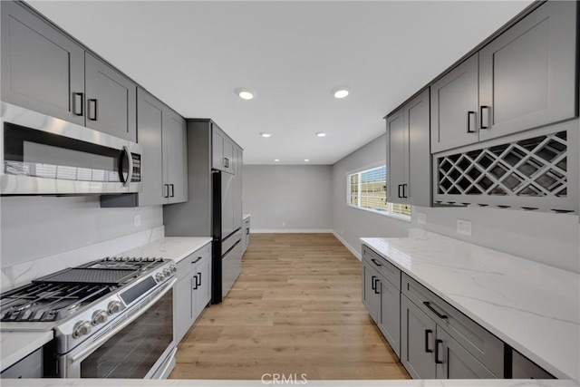 1106 W Bellbrook St, Covina, CA 91722 - kitchen featuring appliances with stainless steel finishes, light wood-style floors, light stone counters, recessed lighting, and gray cabinetry