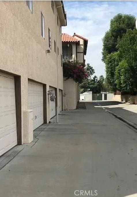 19545 Sherman Way Unit 44, Reseda, CA 91335 - view of side of property with stucco siding, an attached garage, and concrete driveway
