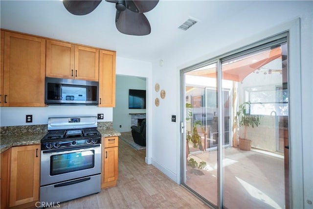 3473 Yankee Cir, Riverside, CA 92503 - kitchen featuring appliances with stainless steel finishes, light wood-style flooring, ceiling fan, and dark stone counters
