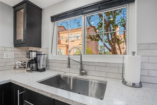4347 Freedom Dr Unit C, Calabasas, CA 91302 - kitchen with dark cabinets, tasteful backsplash, glass insert cabinets, and light stone counters