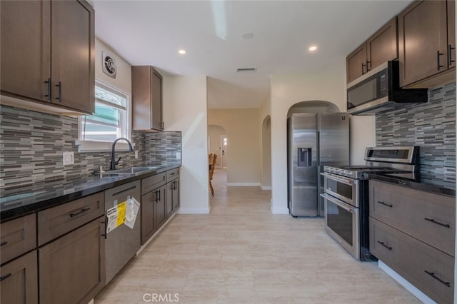 1409 4th St, San Fernando, CA 91340 - kitchen featuring appliances with stainless steel finishes, arched walkways, backsplash, dark stone countertops, and recessed lighting