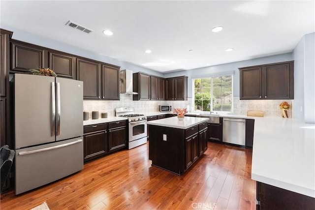 35694 Cherry Bark Way, Murrieta, CA 92562 - kitchen featuring stainless steel appliances, wall chimney exhaust hood, dark brown cabinets, light countertops, and decorative backsplash