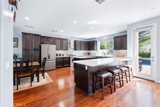 35694 Cherry Bark Way, Murrieta, CA 92562 - kitchen with appliances with stainless steel finishes, dark brown cabinets, light countertops, hardwood / wood-style flooring, and recessed lighting