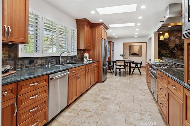 1251 Bryant Rd, Long Beach, CA 90815 - kitchen featuring stainless steel appliances, wall chimney exhaust hood, a skylight, decorative backsplash, and brown cabinetry